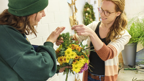 Zwei Personen binden einen bunten Blumenstrauß im Blumenladen im BBW Offenburg