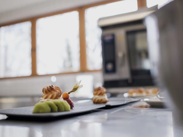 Schön angerichteter Teller mit geschnittener Kiwi, Windbeutel, Eis und einer Physalis 