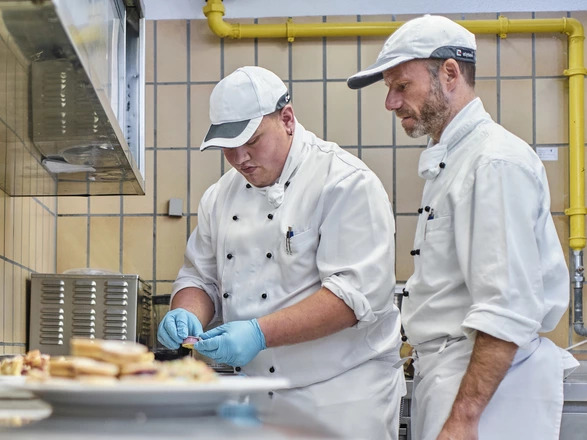 Zwei Personen bei der Speisezubereitung in der Küche