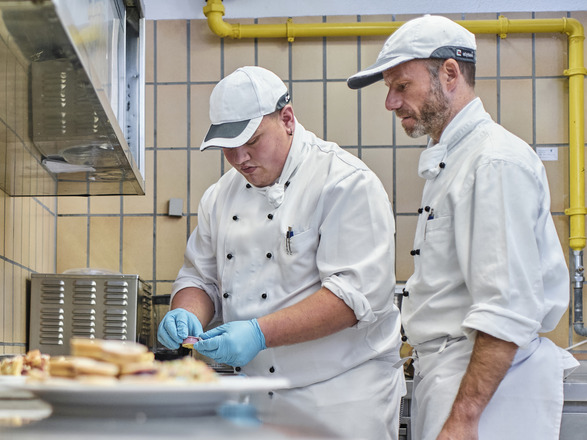 Zwei Personen bei der Speisezubereitung in der Küche