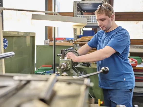 Auszubildender arbeitet an einer Maschine in der Metallwerkstatt